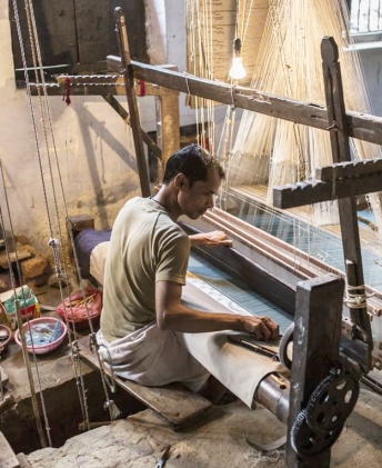 Weaver threading silk on a traditional handloom